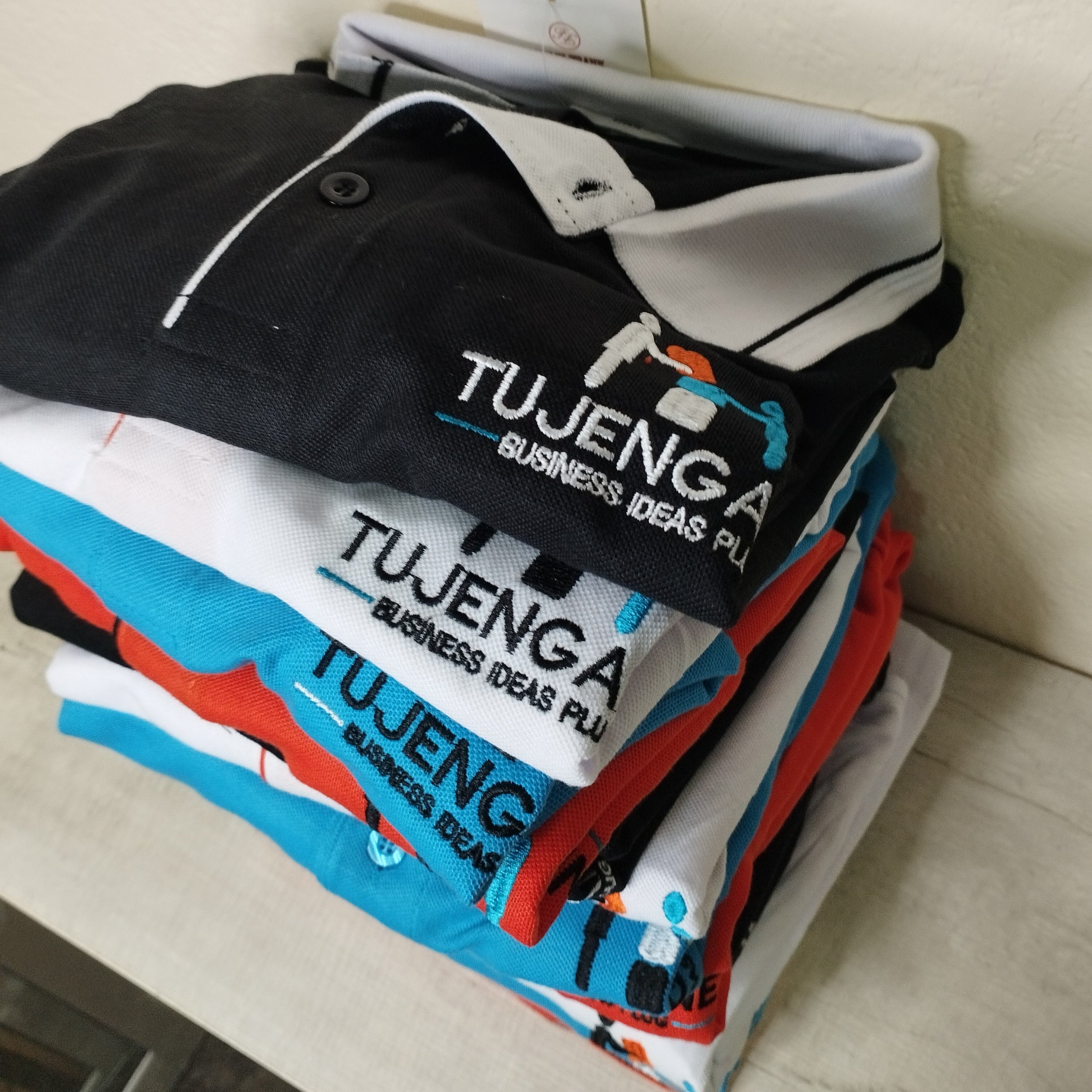 Stack of folded polo shirts with logo embroidery.