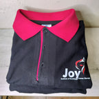 Folded black polo shirt with pink collar .